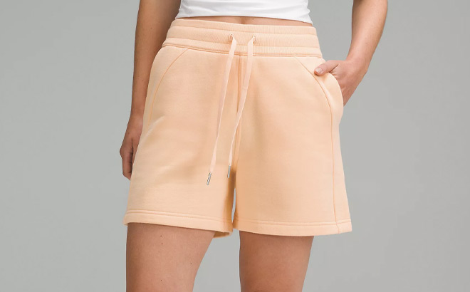 A Person Wearing Lululemon Scuba High Rise Short in Peach Bellini Color A Person Wearing Lululemon Scuba High Rise Short in Peach Bellini Color
