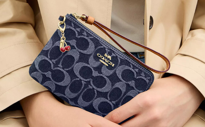 A Person Holding a Coach Corner Zip Wristlet In Signature Denim