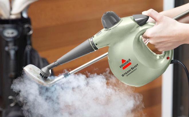 A Woman Cleaning a Gold Club with the Bissell SteamShot Omni Reach Steam Cleaner