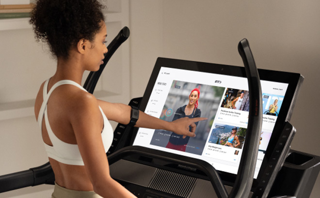 A Girl Watching Workout Programs on a Treadmill Screen