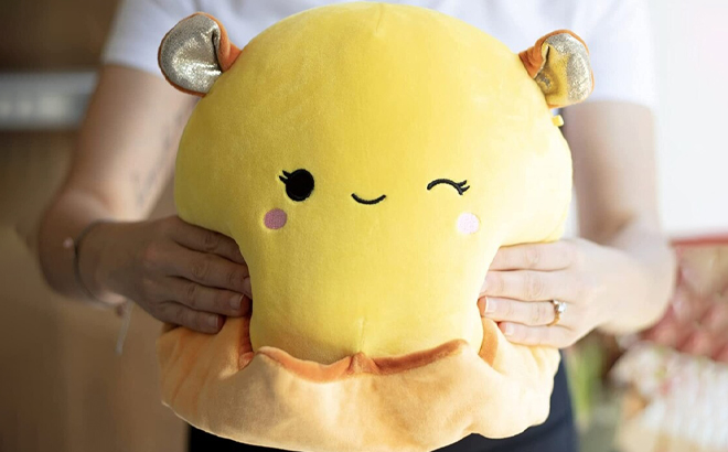 A Person holding Squishmallows 10 Inch Bijan The Yellow Reversible Octopus