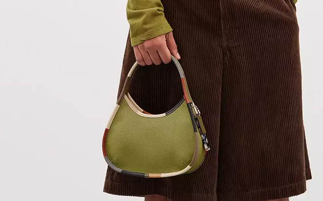 A Man Holding Coach Outlet Ergo Bag In Coachtopia Leather With Colorful Binding