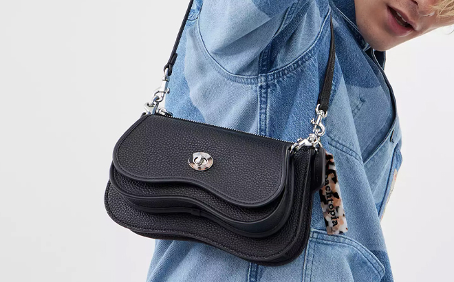 A Man Holding Coach Outlet Wavy Double Pouch Bag In Coachtopia Leather