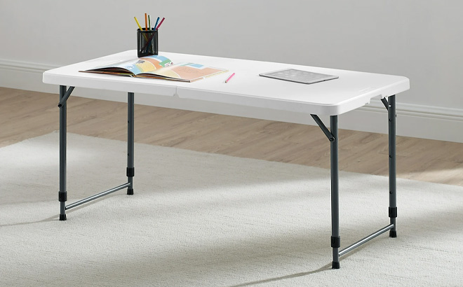 Mainstays White 4 Foot Adjustable Height Folding Plastic Table on the Carpet