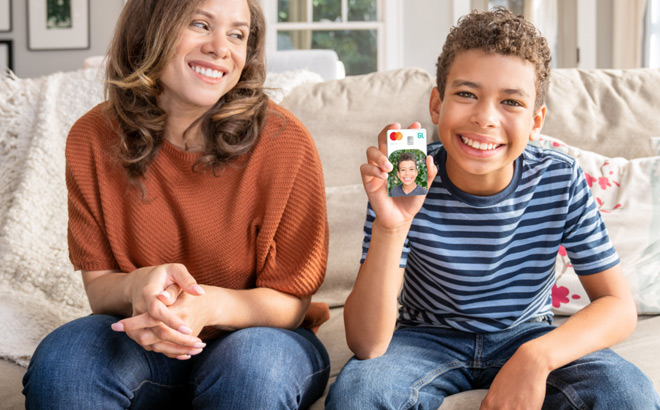 A Boy Holding a Greenlight Debit Card and Sitting on a Couch Next to His Mother A Boy Holding a Greenlight Debit Card and Sitting on a Couch Next to His Mother