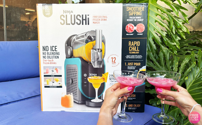 People Holding Drinks in front of Slushi Machine