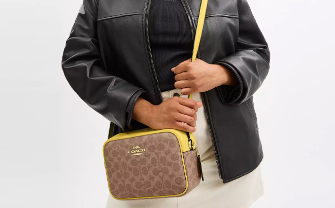 A Woman Wearing Coach Outlet Jamie Camera Bag In Signature Canvas