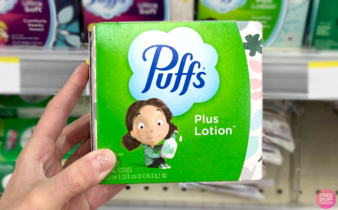 A Hand holding a Box of Puffs Plus Lotion 56 Count Facial Tissues