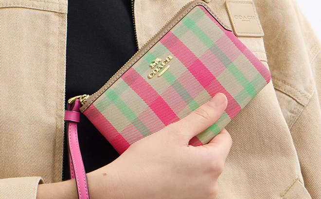 A Person Holding Coach Outlet Corner Zip Wristlet With Plaid Print