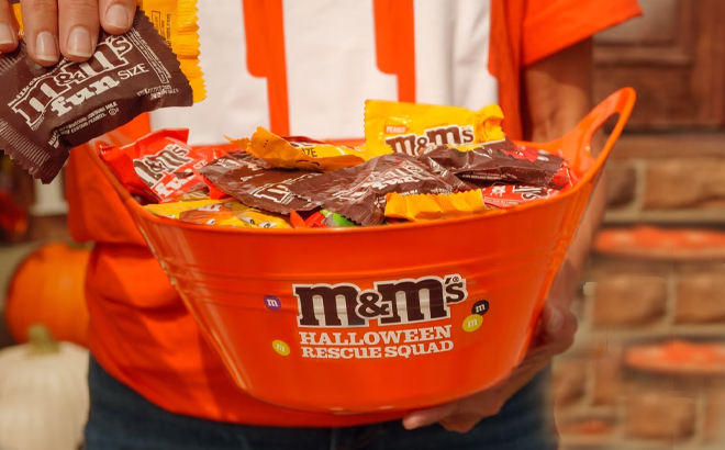 A Person Holding Bucket Filled with MMs Halloween Treats