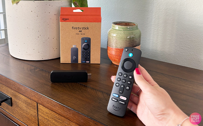 A Person Holding the Amazon Fire TV Stick 4K with Box on a Table A Person Holding the Amazon Fire TV Stick 4K with Box on a Table