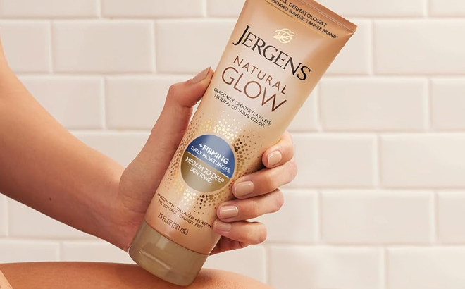 A Person Holding the Jergens Natural Glow Firming Daily Moisturizer Medium to Tan Skin Tones