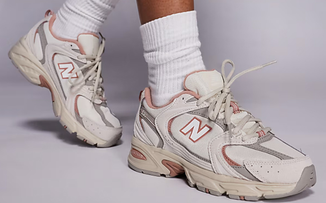 A Woman Wearing New Balance 530 Sneakers in Off White and Coral A Woman Wearing New Balance 530 Sneakers in Off White and Coral