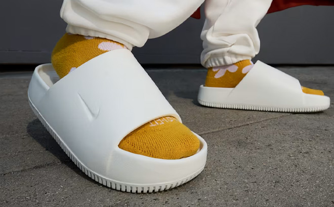 A Person Wearing Nike Womens Nike Calm Slide Sandals in Sail Color A Person Wearing Nike Womens Nike Calm Slide Sandals in Sail Color