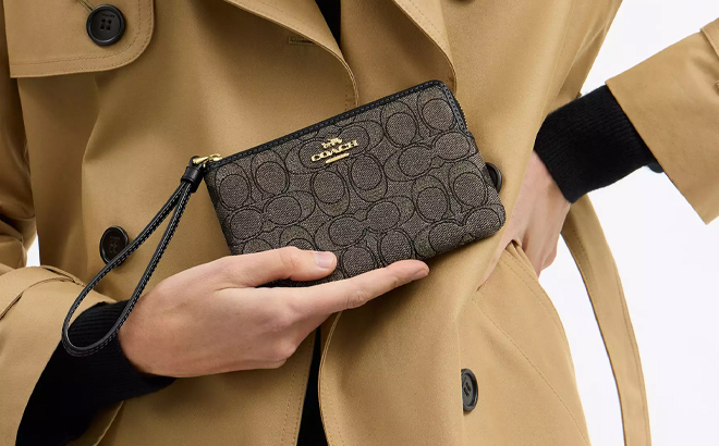 A Woman Holding Coach Outlet Corner Zip Wristlet In Signature Jacquard