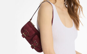 A Woman Wearing Michael Kors Zoe Small Suede Convertible Pochette in Mulberry