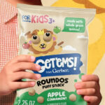 A Person holding a bag of Gerber Getems Roundos Puffs