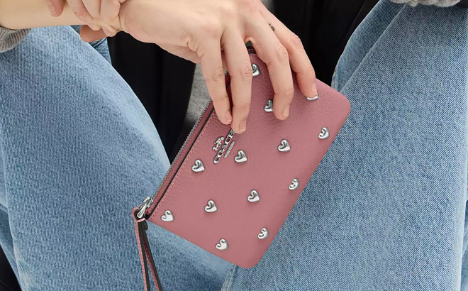 A Woman Holding Coach Outlet Corner Zip Wristlet With Heart Rivets A Woman Holding Coach Outlet Corner Zip Wristlet With Heart Rivets