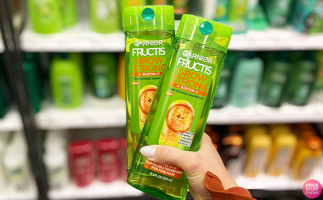 A Person Holding Two Garnier Fructis Grow Strong Thickening Shampoos