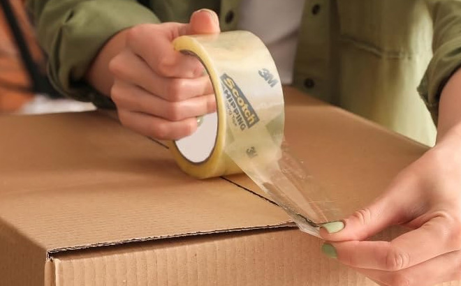 A Person Using Scotch Sure Start Shipping Packaging Tape