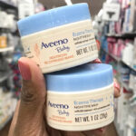 A Woman Holding Aveeno Baby Eczema Therapy Nighttime Moisturizing Balms