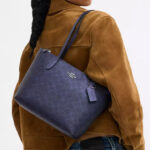 A Woman Wearing Coach Outlet Fiona Zip Tote Bag In Signature Canvas in Blue Navy