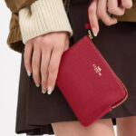 A Woman Holding Coach Outlet Corner Zip Wristlet in True Red