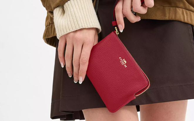 A Woman Holding Coach Outlet Corner Zip Wristlet in True Red