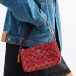 A Woman Holding Coach Outlet Nolita 19 In Signature Denim in True Red
