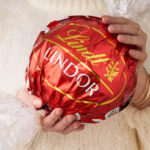 A Person Holding Lindt LINDOR Holiday Milk Chocolate Truffle Candy Maxi Ball