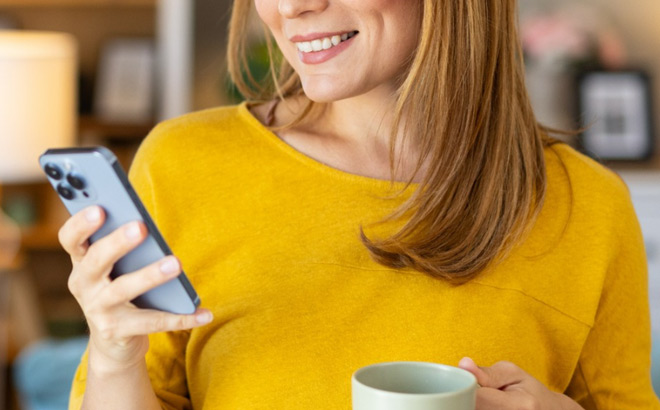 A Woman Looking at Her iPone and Drinking Coffee