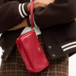 A Woman Holding Coach Outlet Nolita 19 Bag in Poppy Color