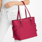 A Woman Holding Michael Kors Voyager Large Saffiano Leather Tote Bag in Raspberry