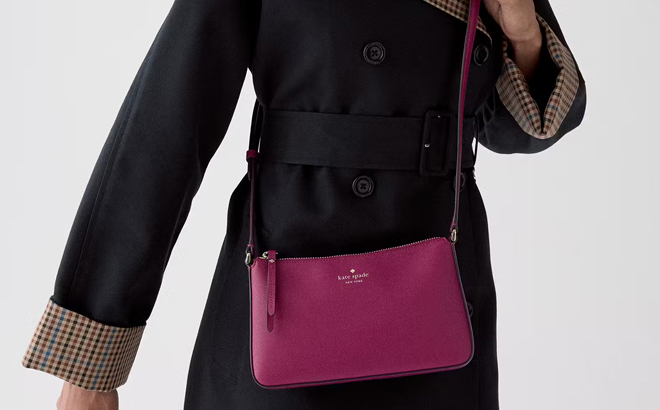 A Woman Wearing Kate Spade Ginnie Crossbody Bag in Dark Raspberry