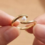 A Person Holding Genevieve Minimalist 14k Gold Plated Dainty Pearl Elegant Slim Band Ring