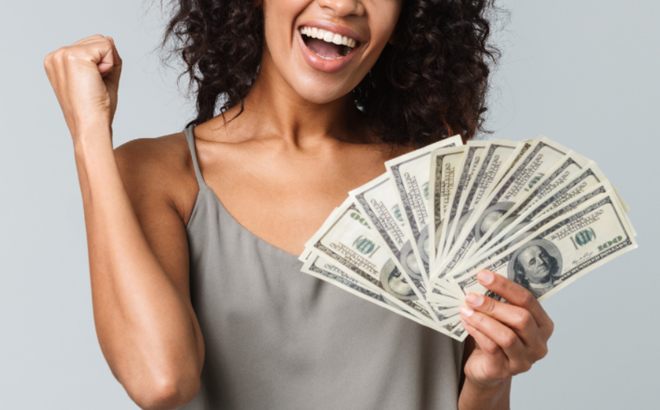 A Woman Celebrating While Holding a Fan of Cash