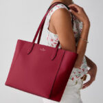 A Woman Wearing Kate Spade Dana Tote Bag in Red Jam