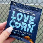 A Person Holding a Small Bag of Love Corn Sea Salt Crunchy Roasted Corn Snack