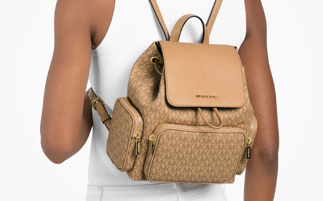 A Woman Wearing Michael Kors Merritt Small Signature Logo Cargo Backpack in Camel