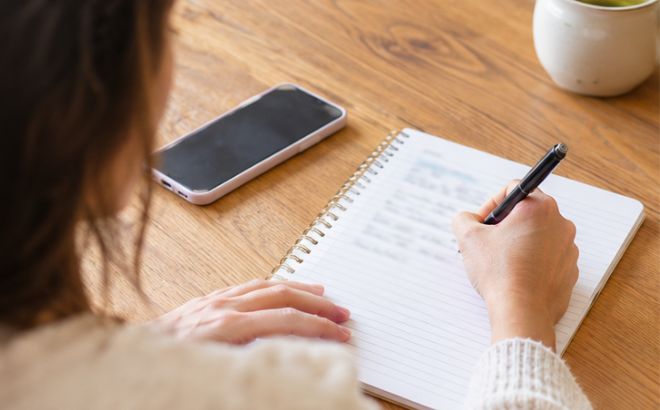 A Woman Writing a Budget in a Notebook A Woman Writing a Budget in a Notebook
