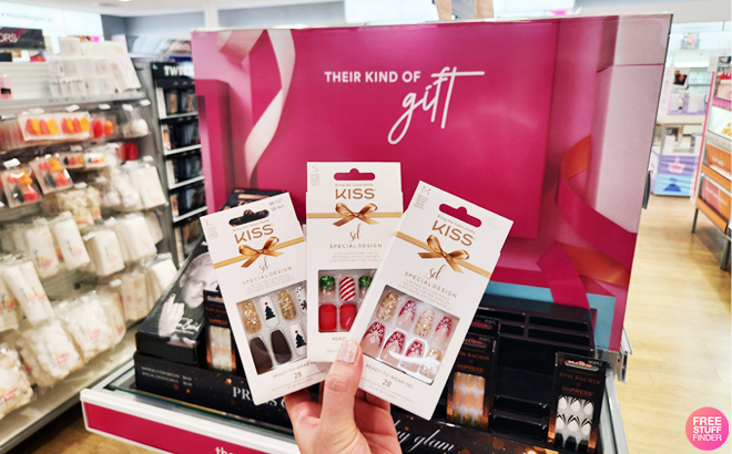 A Hand Holding Three KISS imPRESS Press-On Manicure Sets at a Store